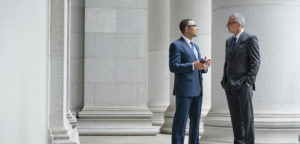 Full length view of businessmen standing and talking under pillars of ornate building